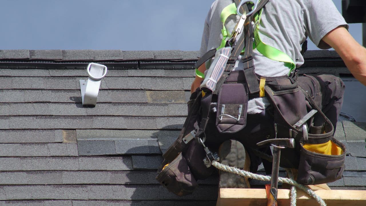 Roofers in safety harnesses on a roof