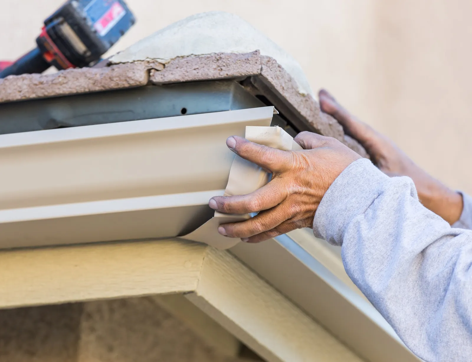 Hands fitting a section of gutter at the roof edge