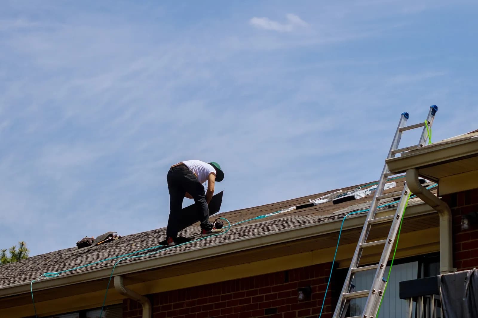A worker repairing a section of shingle roof