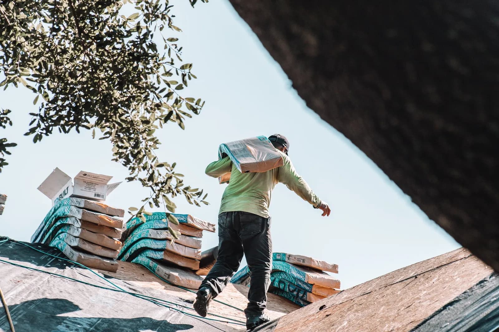 A roofer carrying a bundle of shingles