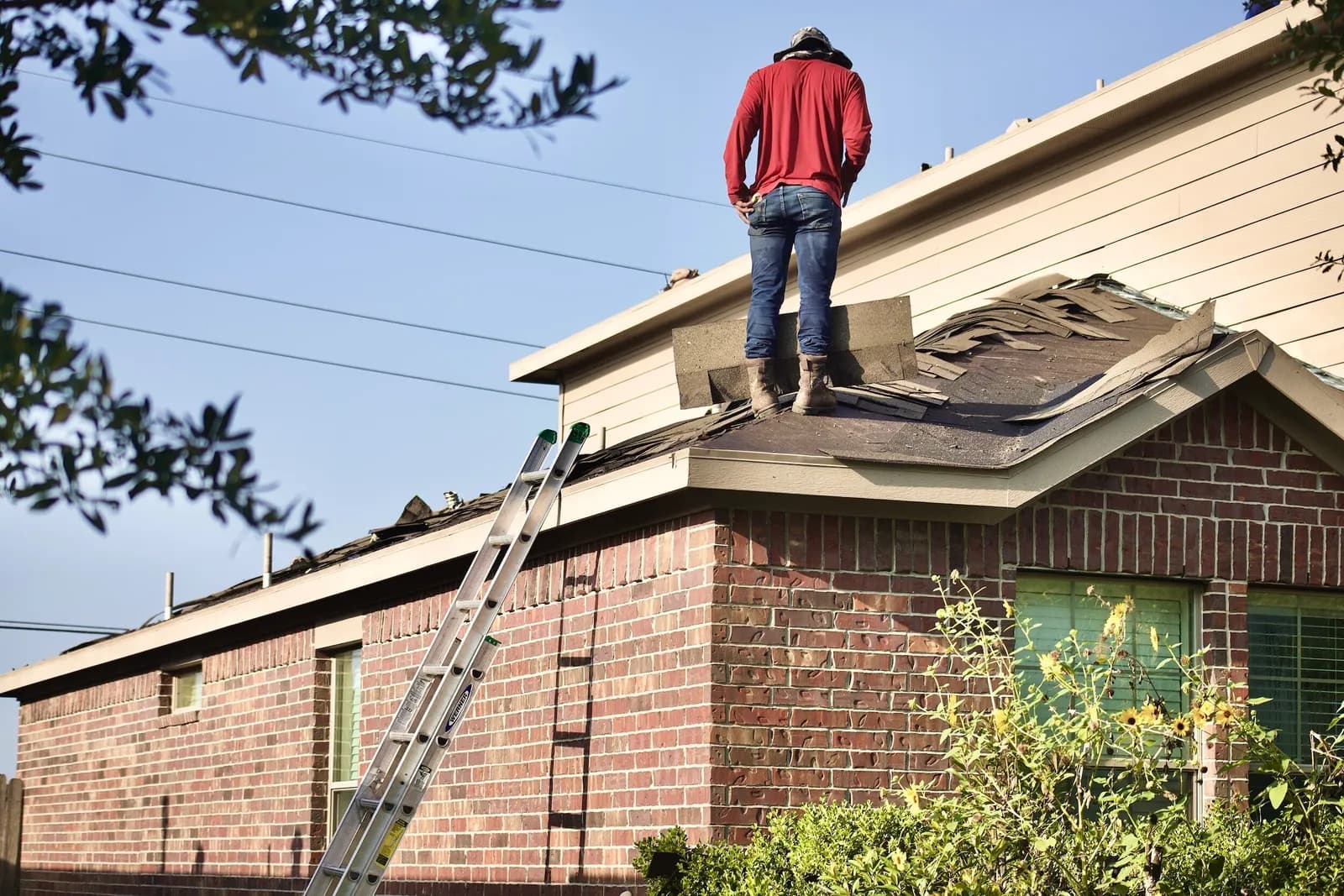 A roofer on the roof of a brick home