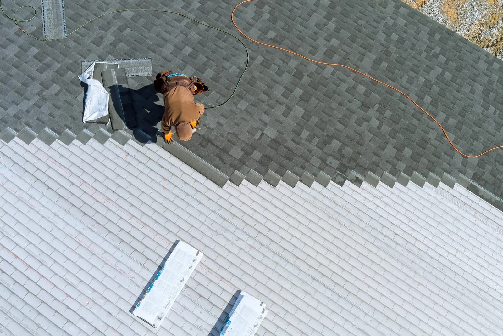 A worker installing shingles on a home